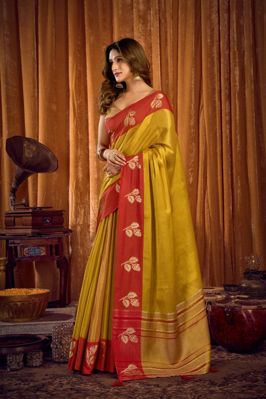 Woman in a yellow and red saree standing in front of a vintage record player and curtains.